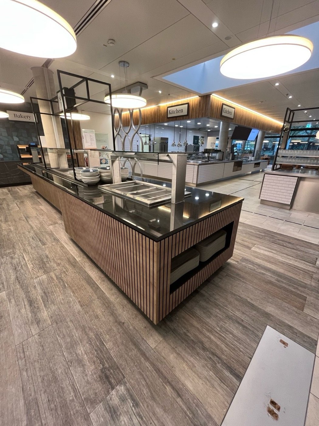 Buffet and serving counter with slatted front and stone top in front of the live-cooking stations